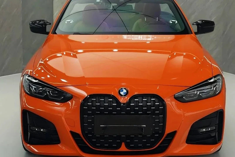Orange BMW front view with gloss-black grille, mirror caps and adjacent painted panels visible